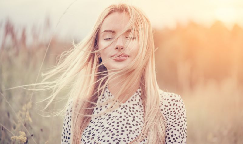 Piękna młoda kobieta z blond włosami na tle zachodzącego słońca | Hemorigen femina